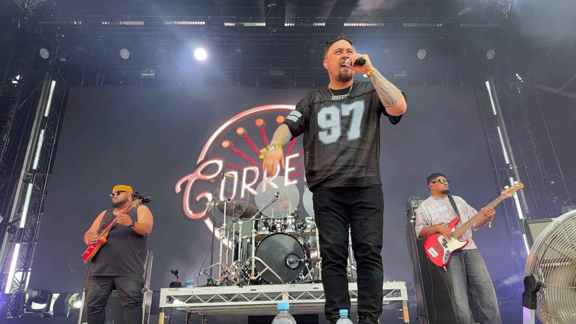 A singer in a number 97 jersey fronting a band on an outdoor stage